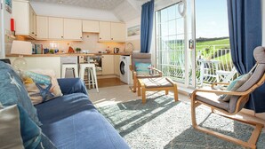 A cozy living room with a sofa, chairs, and a view of a garden through a sliding glass door. - 3 bedroom accommodation in Hope Cove, near Kingsbridge (Hope Cove, near Kingsbridge)