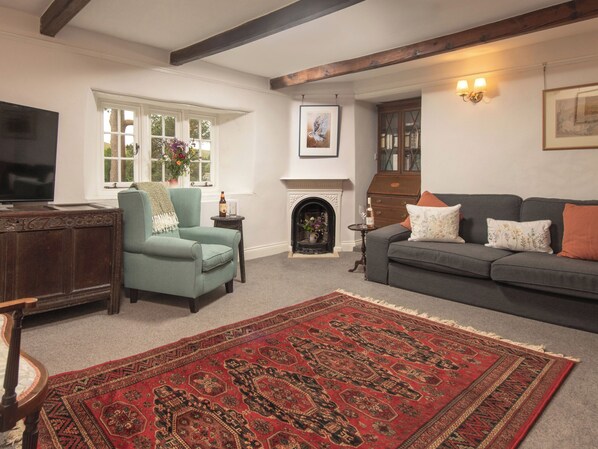 A living room with a sofa, armchair, fireplace, and a television.