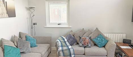 A living room with two sofas, a coffee table, a radiator, and a bookshelf.
