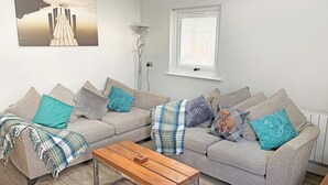 Ein Wohnzimmer mit einer Sofagarnitur, einem Couchtisch und einem Bild an der Wand.