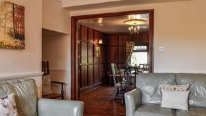 A room with a wooden door, a dining table with chairs, and a sofa with decorative pillows. - The Granary - UK45181 (Newcastleton)