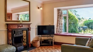 A living room with a fireplace, a television, and a window with curtains. - The Granary - UK45181 (Newcastleton)
