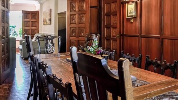 A dining area with a wooden table and chairs, a decorative vase, and a door with intricate paneling. - The Granary - UK45181 (Newcastleton)