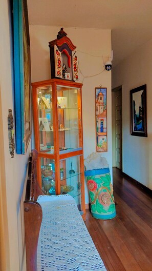Um corredor com um armário de madeira, uma vitrine de vidro e uma almofada colorida.