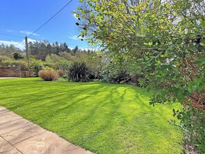 A well-maintained lawn with a stone wall and various shrubs.