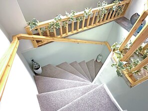 A spiral staircase with wooden railings and green plants.