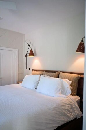 Relax in a serene space with a comfortable bed and classic lamps.