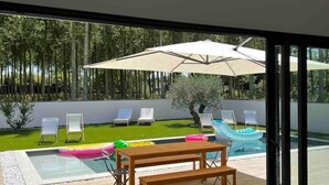 Ein moderner Poolbereich im Freien mit einer Holzbank, Liegestühlen und Sonnenschirmen.