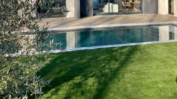 Ein modernes Haus mit Swimmingpool, Terrasse und Blick ins Innere.