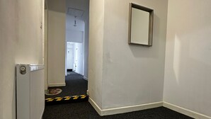 A narrow hallway with a radiator, a caution tape barrier, and a mirror on the wall. - Blackwood Residence (Accrington)