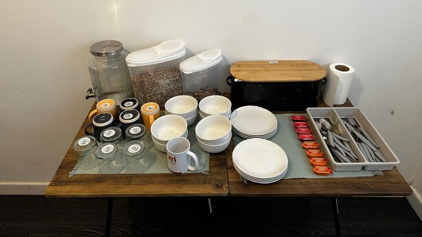 A table with various kitchenware items including bowls, plates, cups, and utensils. - Blackwood Residence (Accrington)