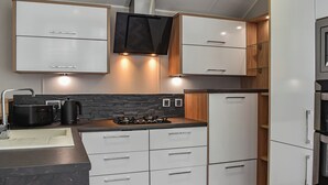 Une cuisine moderne avec des meubles blancs, une cuisinière à gaz, un plan de travail noir et un four encastré.