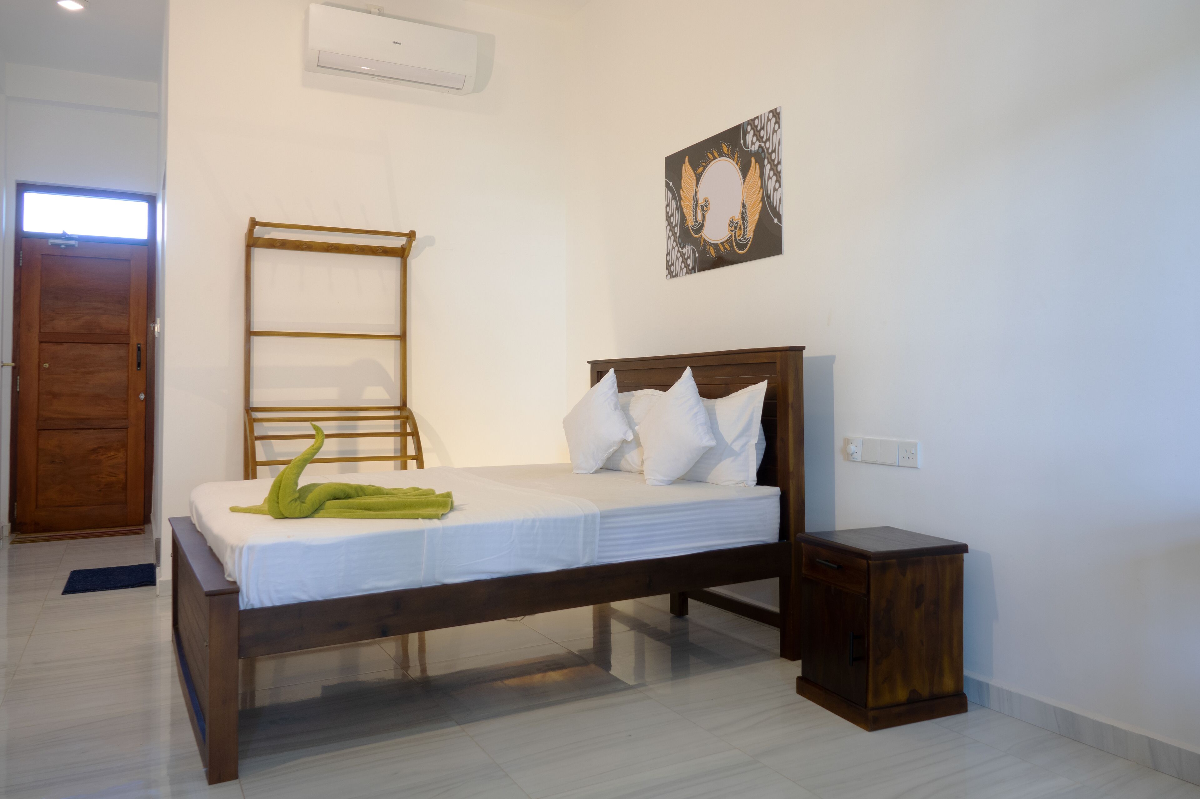 Un dormitorio con una cama de madera, una mesita de noche pequeña y un aire acondicionado instalado en la pared.
