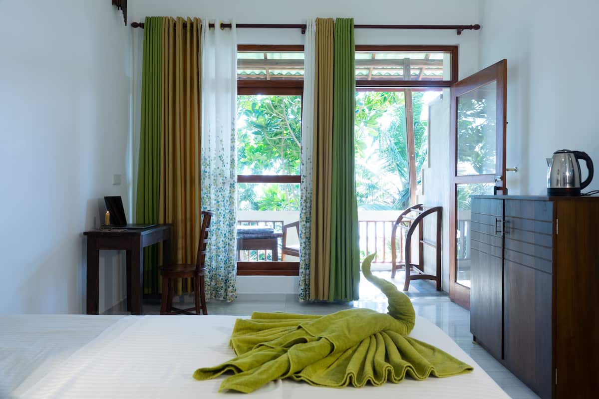A room with a bed, a desk, a chair, a wardrobe, and a view of the outdoors.