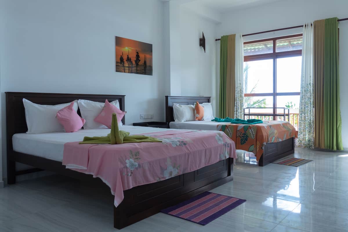 A hotel room with two beds, a large window with curtains, a painting on the wall, and a tiled floor.