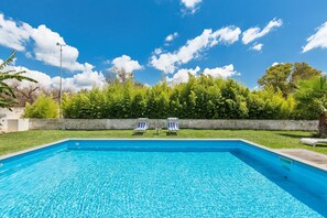 Relax by the pool surrounded by lush greenery and comfortable lounge chairs.