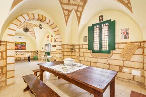 Enjoy dining and socializing in this charming room with a vaulted ceiling and exposed brickwork, featuring a wooden table and comfortable seating options.