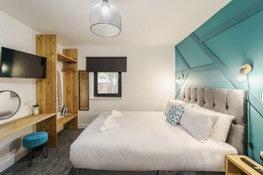 A modern bedroom with a large bed, a wooden desk, a TV, and a window. - Deluxe Studio Apartments (Derby)