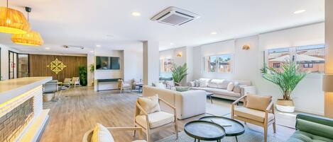 A spacious lobby with a reception desk, seating area, and large windows offering views of the outside.