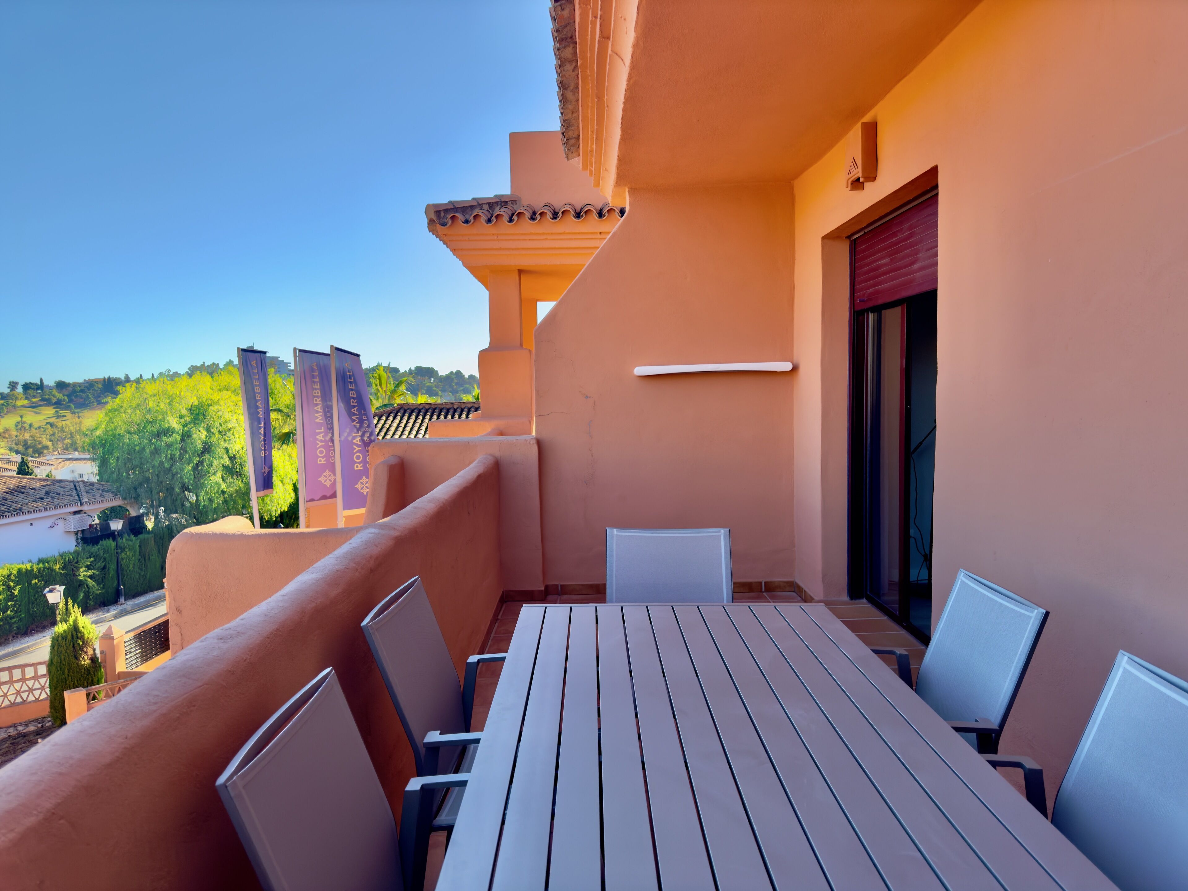 Ein Balkon mit Tisch und Stühlen, mit Blick auf eine malerische Flusslandschaft.
