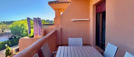 Ein Balkon mit Tisch und Stühlen, mit Blick auf eine malerische Flusslandschaft.