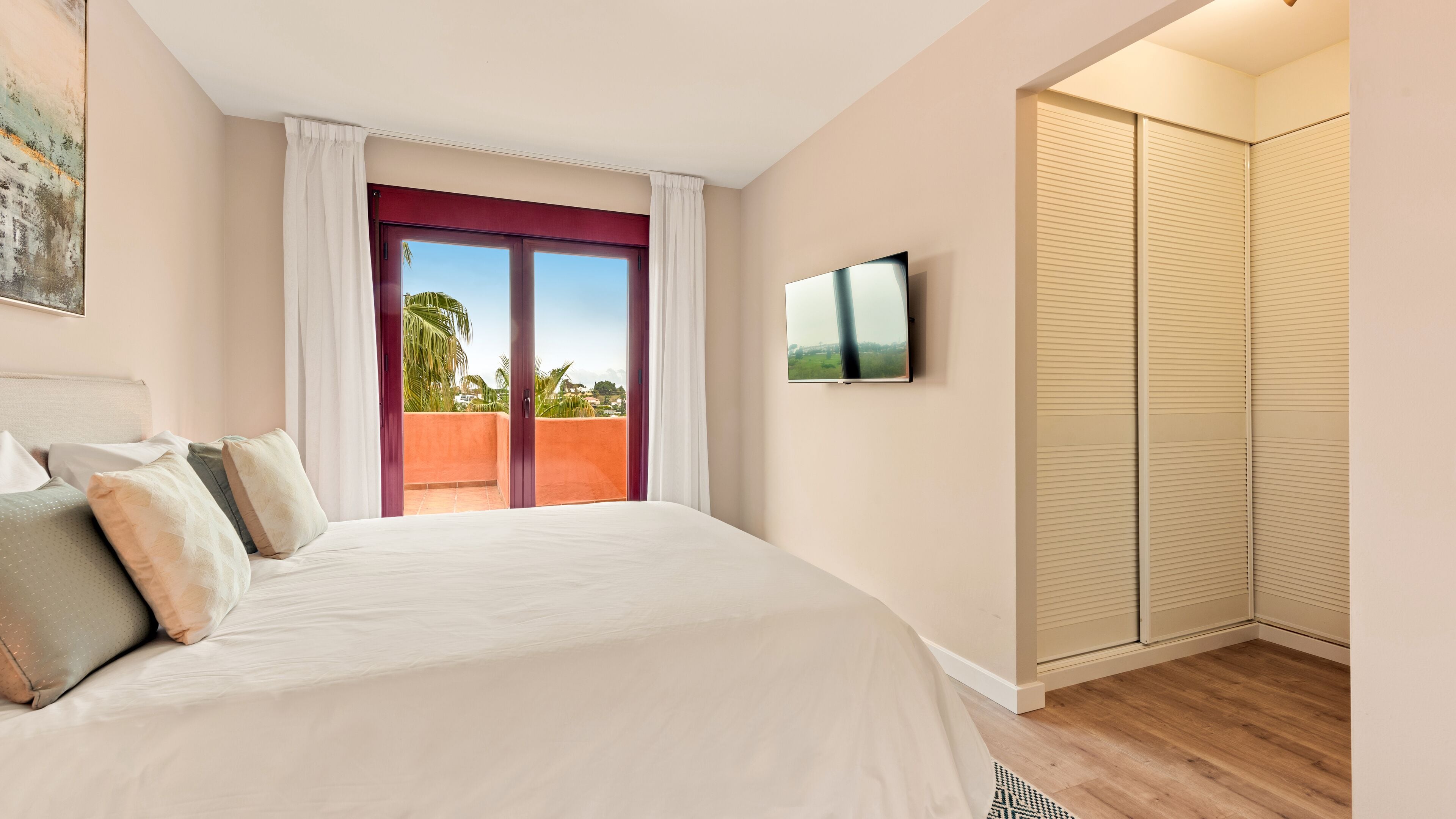 A hotel room with a large bed, a TV mounted on the wall, and a sliding door closet.
