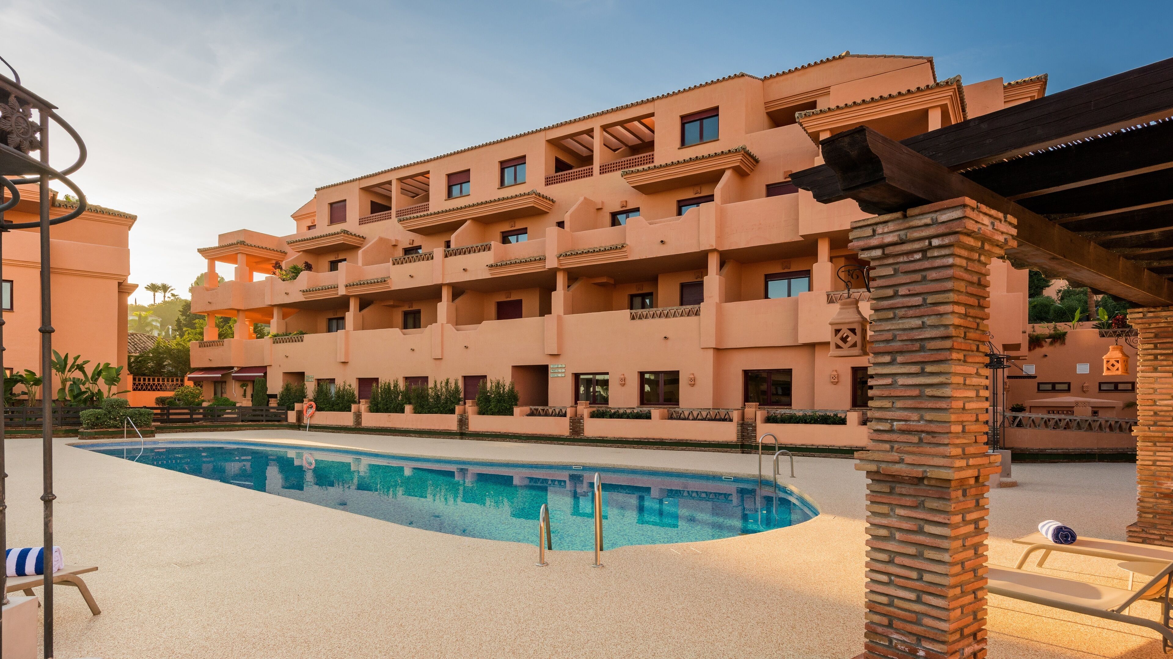 A hotel with a swimming pool, multiple balconies, and a brick facade.