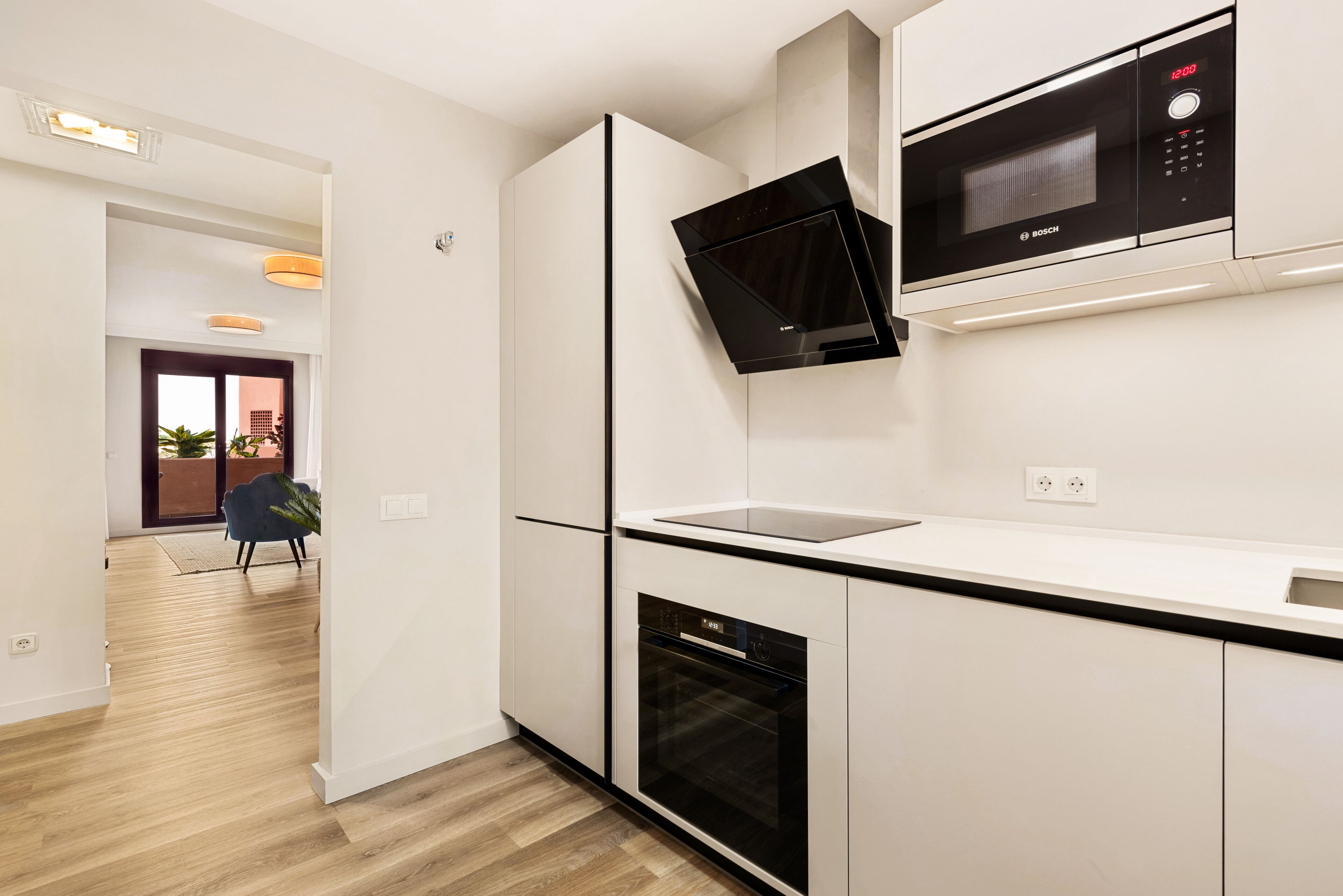 Een moderne keuken met witte kastjes, een Bosch magnetron en een inbouwoven.