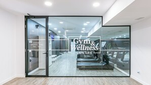 Un gimnasio y centro de bienestar con puertas de cristal, suelo de madera y equipamiento de ejercicio visible a través del vidrio.