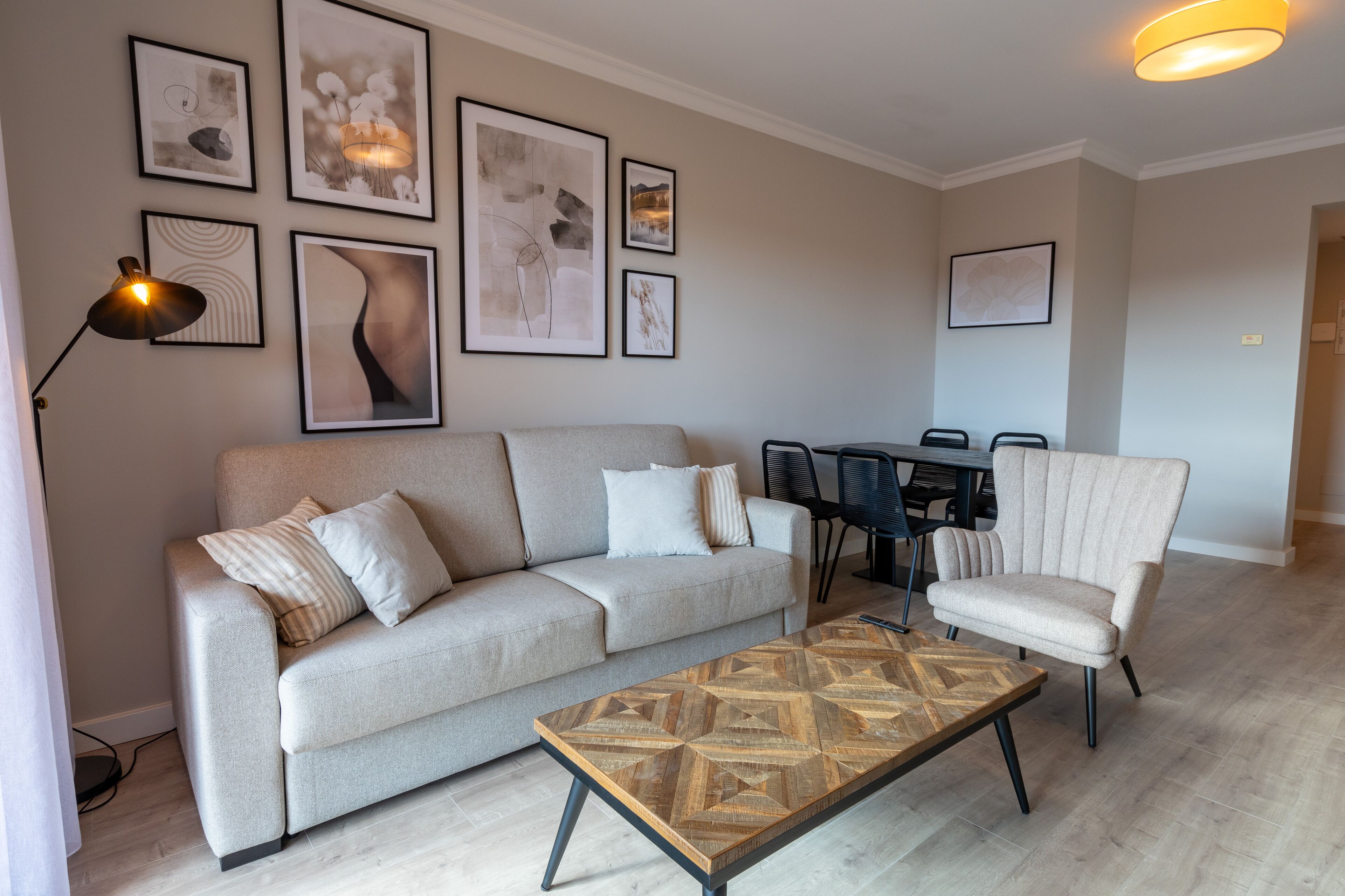 Una sala moderna con sofá, sillón, mesa de centro y comedor.