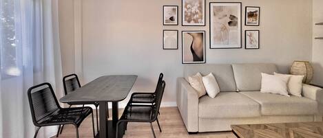 A modern living room with a dining area, featuring a sofa, a coffee table, and a dining table with chairs.