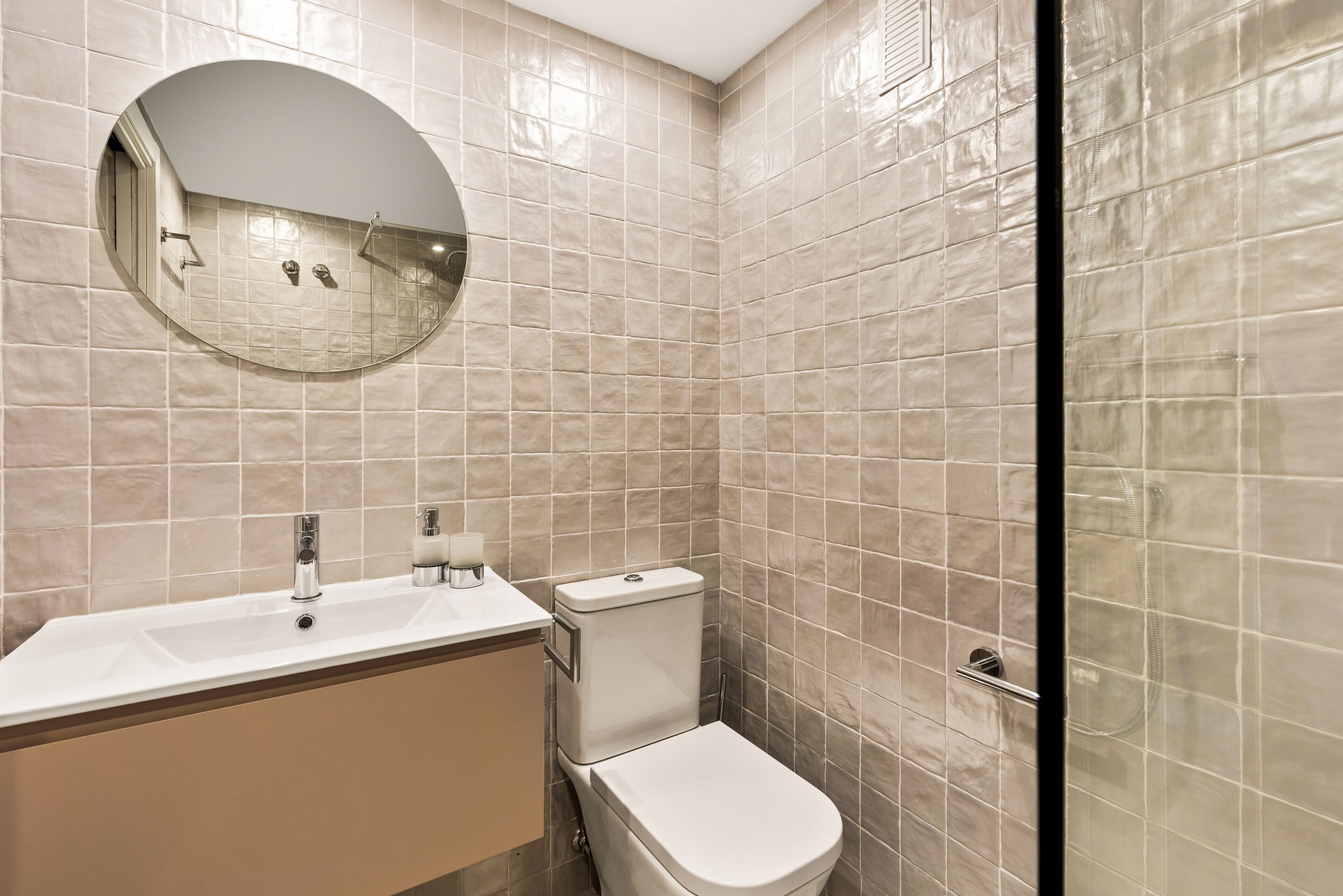 Un baño con lavamanos, espejo e inodoro.