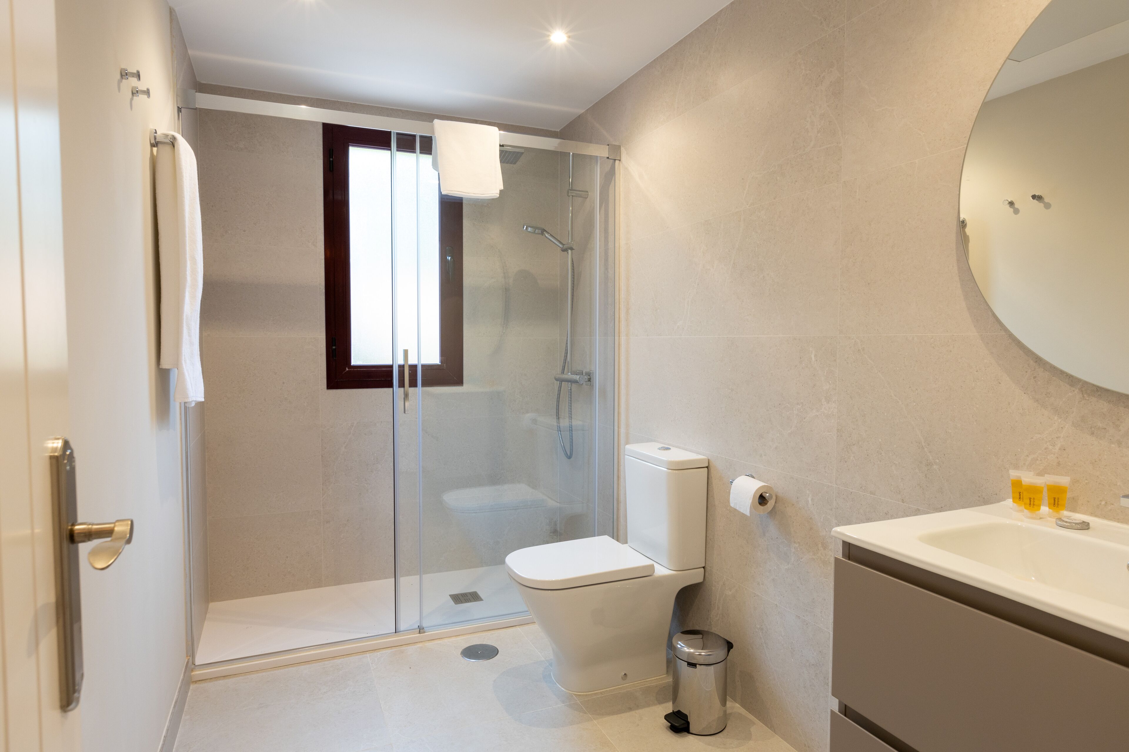 A modern bathroom with a glass-enclosed shower, a toilet, and a sink with a mirror above it.