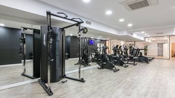 Un gimnasio moderno con diverso equipo de ejercicio, que incluye una jaula de sentadillas, cintas de correr y bicicletas estáticas.