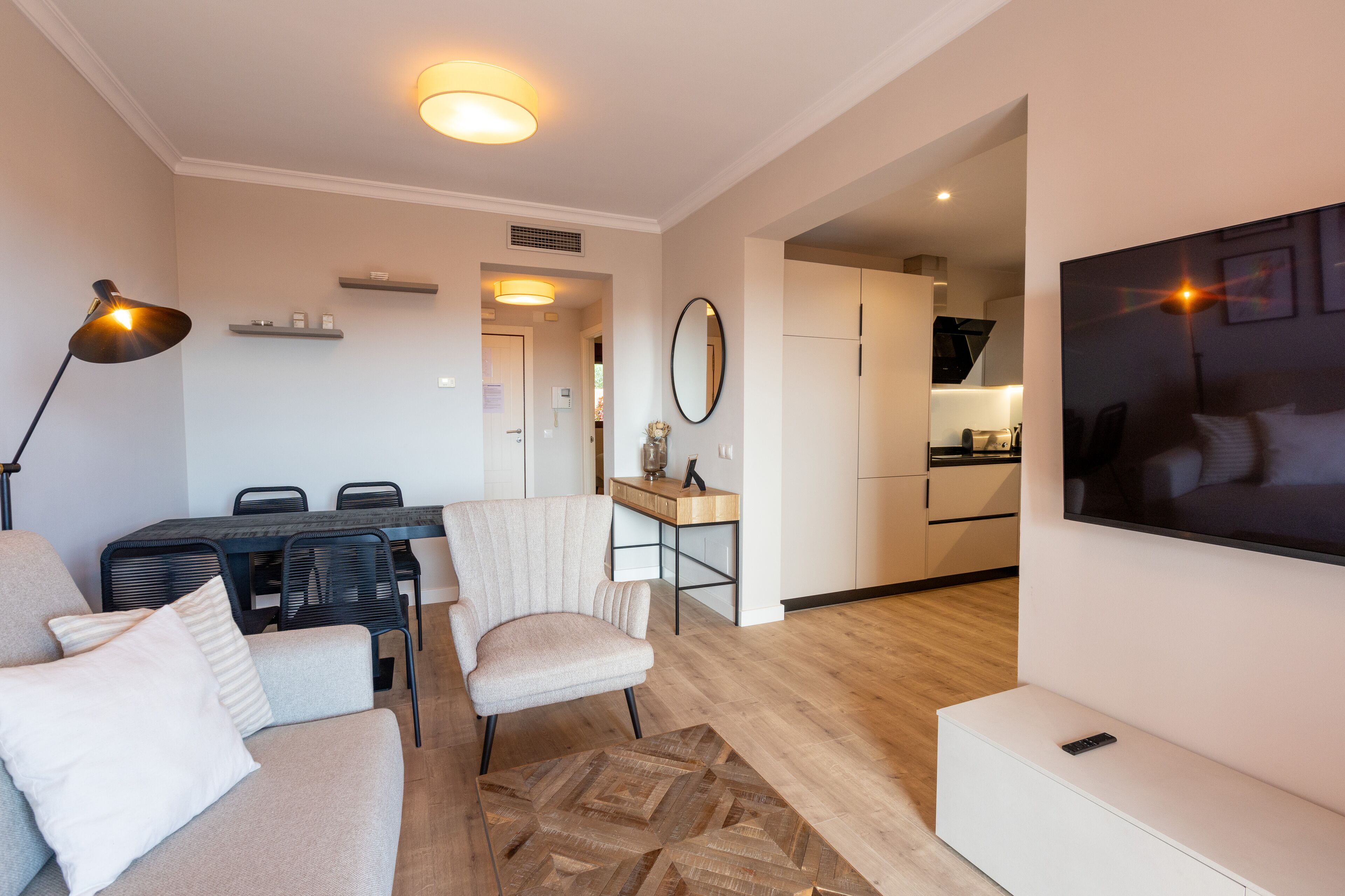 A modern living room with a sofa, a dining table, and a TV.