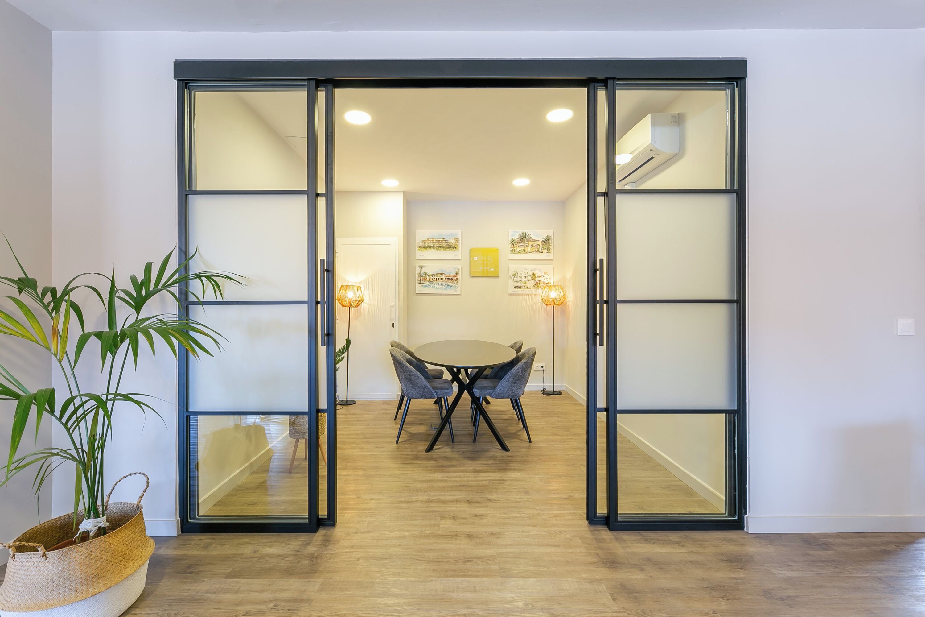 A room with a sliding glass door leading to a dining area with a round table and chairs.