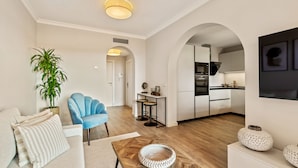 Una sala de estar moderna con un sofá, un sillón azul, una mesa de centro y una planta en maceta.