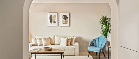A living room with a sofa, a coffee table, a blue armchair, and two abstract paintings on the wall.