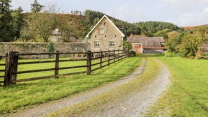 A rural landscape with a stone building, a wooden fence, and a gravel path. - Red Kite Lodge (Llandeilo)