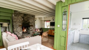 A cozy living room with a stone fireplace, a dining area with a table set for tea, and a kitchen with a sink and cabinets. - Red Kite Lodge (Llandeilo)