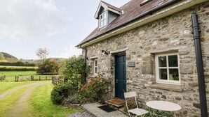 A stone building with a dark blue door, a small porch, and a sign reading "Llewelyn's Barndor". - Red Kite Lodge (Llandeilo)