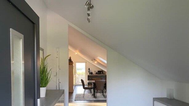A modern kitchen with a dining area, a staircase leading to an upper level, and a view of the outdoors. - roof terrace flat "Alois" (Passau)