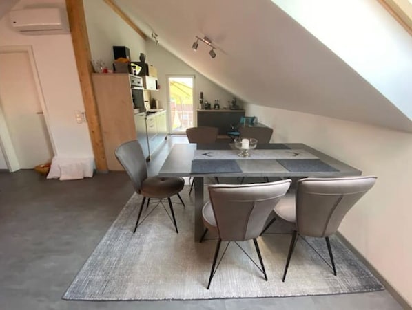 Uma sala de jantar com uma mesa, quatro cadeiras e um tapete.