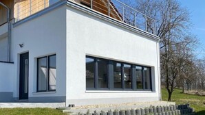 A modern two-story house with a white exterior, large windows, and a wooden balcony. - roof terrace flat "Alois" (Passau)
