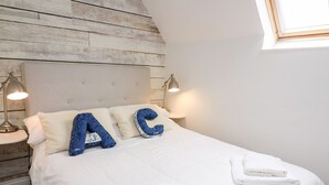 Una cama bien hecha con sábanas blancas y almohadas azules que forman las letras 