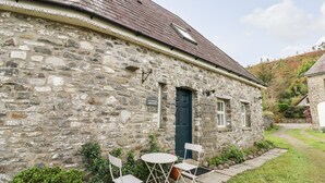 A stone building with a dark blue door, a small window, and a sign that reads "T.Y. Cnchur's Cnchur House."