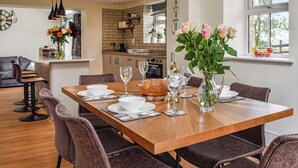 A dining area with a wooden table set for four, surrounded by chairs. - 3 bedroom accommodation in Lancaster (Lancaster)