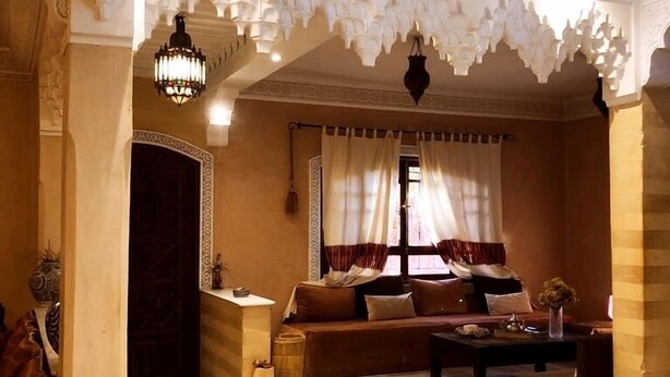 A luxurious living room with a curved seating area, ornate ceiling, and traditional decor.