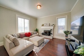 Una sala de estar con un sofá color crema, una chimenea y un televisor.