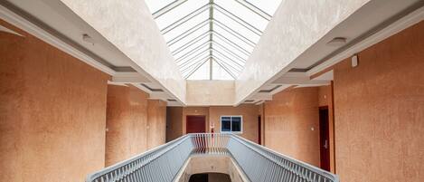 A modern interior with a central staircase, a skylight, and a directional exit sign.